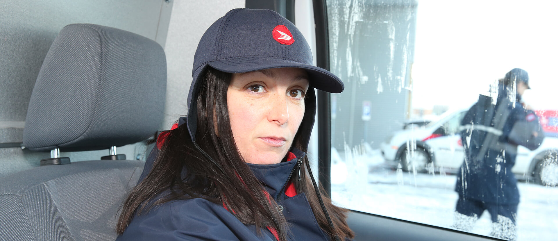 Travailleuse des postes au volant d’un camion de livraison regardant directement l’appareil photo d’un air sérieux. Travailleuse des postes au volant d’un camion de livraison regardant directement l’appareil photo d’un air sérieux.