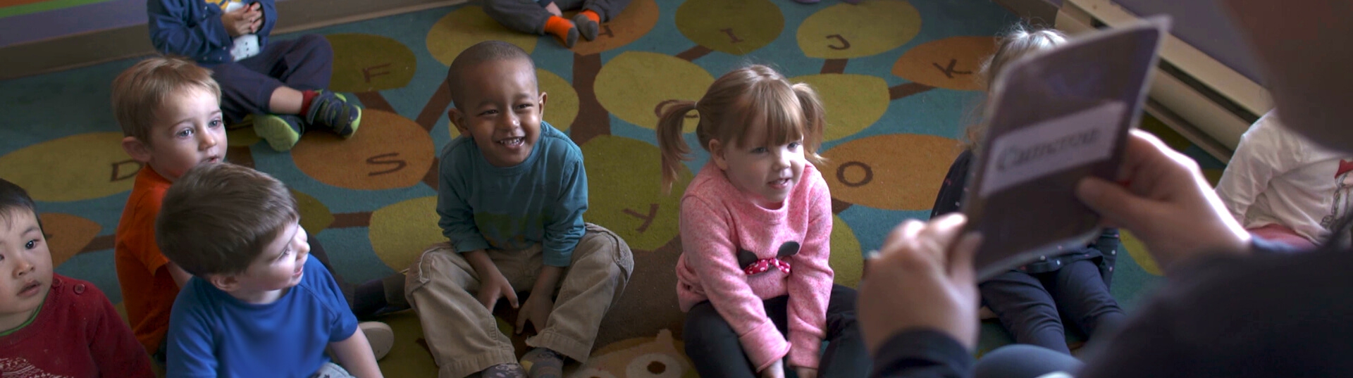Children sitting on a carpet during circle time at a day care.